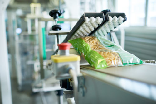 Close up of production process at modern food factory, focus on macaroni bag ready for packaging sliding down assembly line, copy space